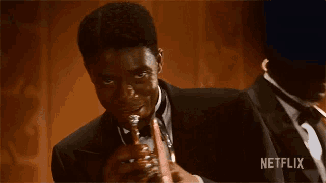 a man in a tuxedo is playing a trumpet with a netflix logo in the corner