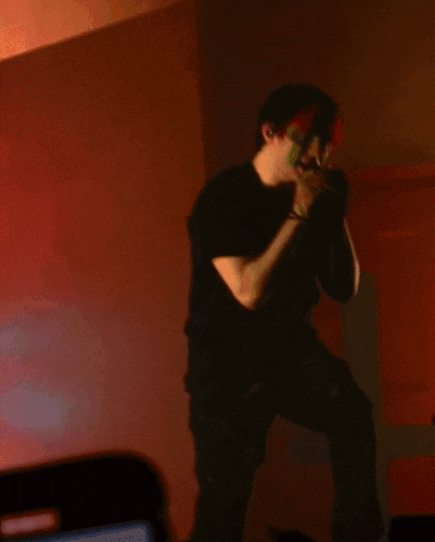 a man with red hair and green paint on his face singing into a microphone