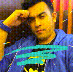a man wearing a blue jacket and a batman shirt is sitting in a chair