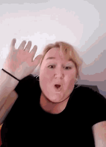 a woman in a black shirt is making a funny face with her mouth open