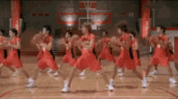 a group of basketball players wearing red uniforms are dancing on a court .