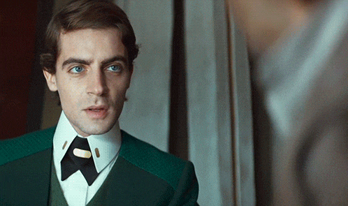 a man in a green suit and tie has a button on his collar that says ' a ' on it