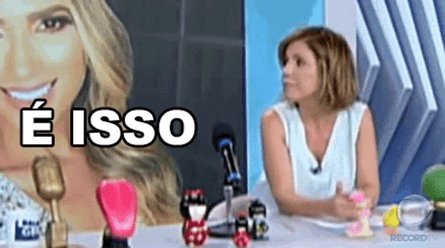 a woman sitting at a table with a picture of a woman behind her and the words " e isso " on the bottom