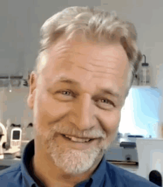 a man with a beard is smiling for the camera .