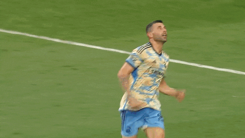 a soccer player is celebrating a goal on the field while another player lays on the ground .