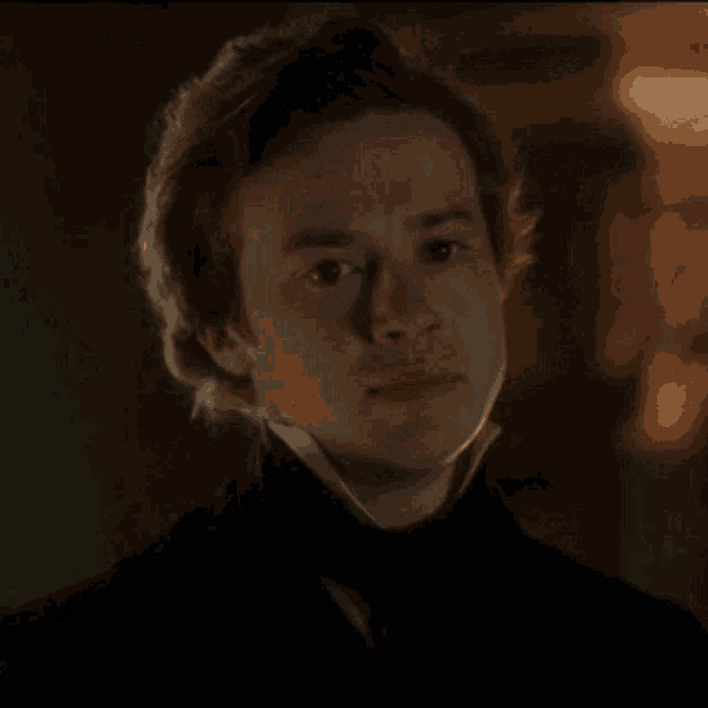 a man in a black suit and tie is looking at the camera .