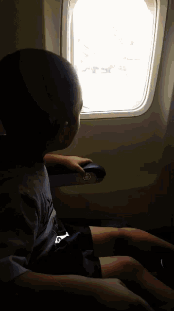 a child is sitting on an airplane looking out the window