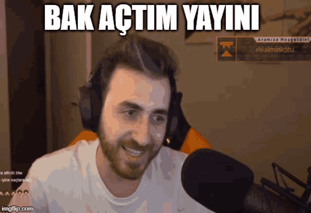 a man wearing headphones is smiling in front of a microphone with the words bak actim yayini written above him