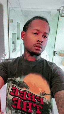 a man taking a selfie with a shirt that says ' black shit ' on it