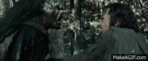 a man is holding a sword in a forest while another man is holding a sword .