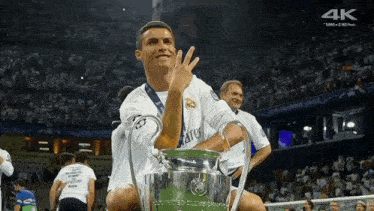 a soccer player holds a trophy in front of a crowd that says 4k on the bottom