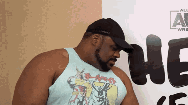 a man wearing a hat and a tank top stands in front of a sign that says all elite wrestling