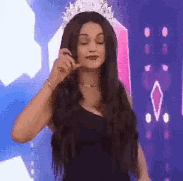a woman wearing a tiara and a black dress is making a funny face .