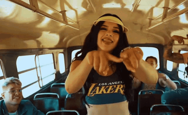 a woman wearing a los angeles lakers tank top is pointing at the camera
