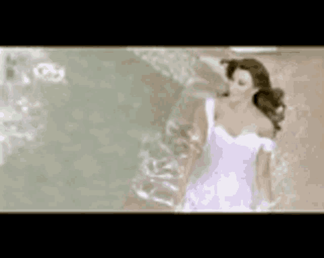a woman in a white dress is walking in the water .