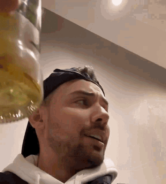 a man with a beard is holding a bottle of liquid in his hand