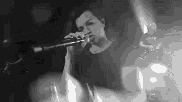 a man is singing into a microphone in a black and white photo .