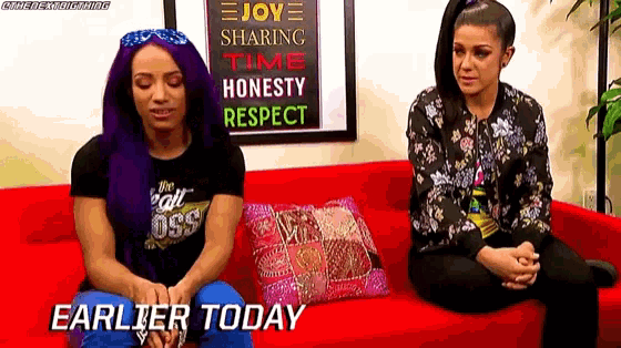two women are sitting on a red couch with the words earlier today written on the bottom