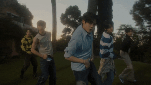 a group of young men are standing in a field with trees in the background