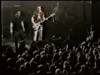 a man is playing a guitar on stage in front of a crowd of people .