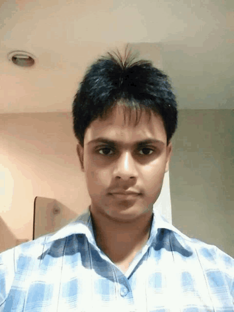 a man in a blue plaid shirt is looking at the camera