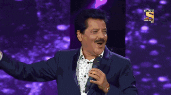 a man in a suit singing into a microphone with a sony logo in the background