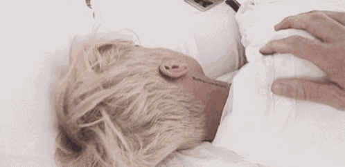 a person is touching a person 's neck while they are laying in bed .