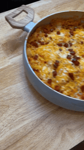 a pan of food with a wooden handle is sitting on a wooden table