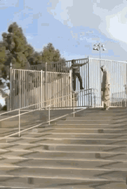 a person is doing a trick on a skateboard over a fence while another person watches .