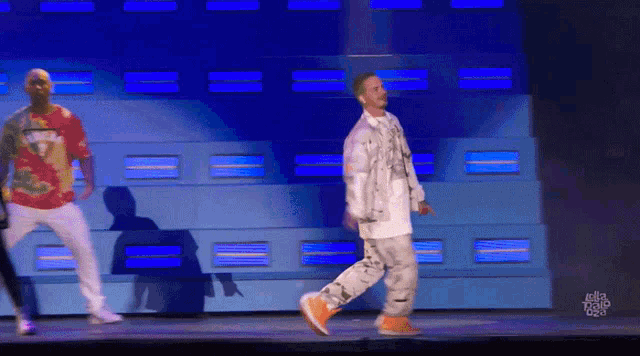 two men are dancing on a stage and one has a shirt that says ' gmt ' on it