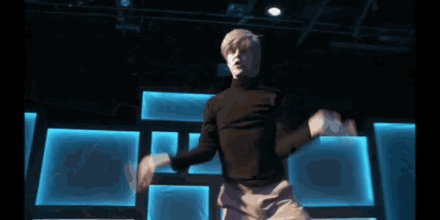 a man in a black turtleneck stands on a stage