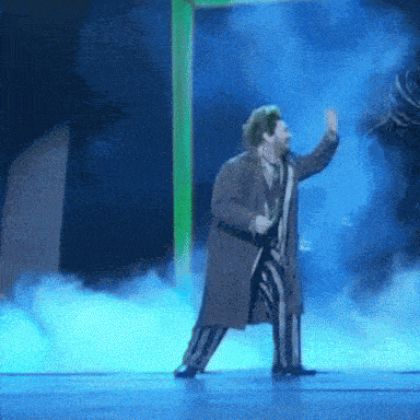 a man in a striped suit is dancing on stage