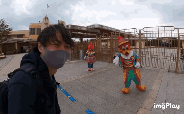 a man wearing a mask stands in front of a clown and a fence that says imgplay on the bottom