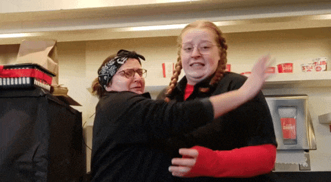 a woman in a bandana is hugging another woman in a kitchen
