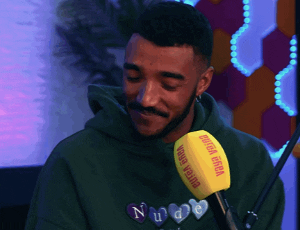 a man wearing a green hoodie is talking into a yellow microphone that says ' chiara ferra ' on it