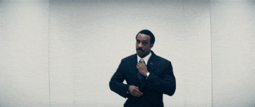 a man in a suit and white shirt is tying his tie