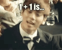 a man in a suit and bow tie is saying 1 + 1 is .