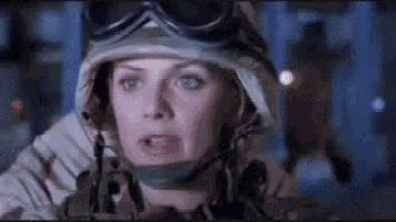 a woman in a military uniform and helmet is looking at something .