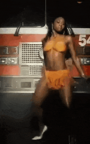 a woman in a bikini is dancing in front of a fire truck number 54