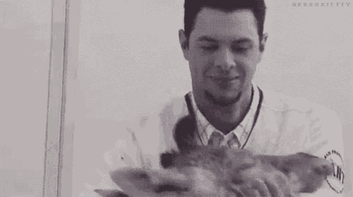 a man is holding a giraffe 's head and smiling .