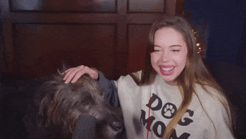 a woman petting a dog while wearing a sweater that says dog