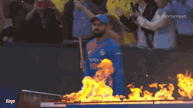a man in an oppo shirt is standing in front of a fire