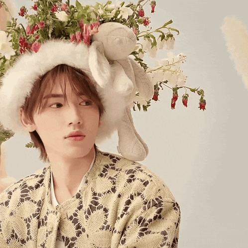 a man wearing a hat with flowers and a stuffed animal on it