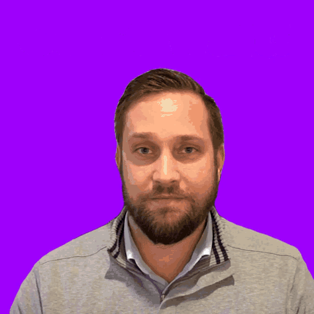 a man with a beard is standing in front of a purple background that says " can 't wait "