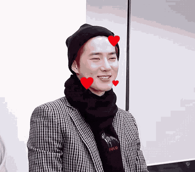 a young man wearing a polo sweater and a beanie with hearts on his face
