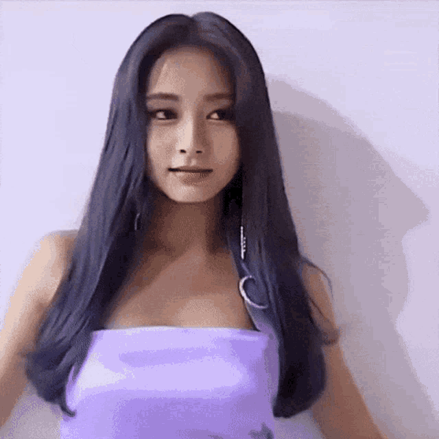 a woman with long black hair is wearing a purple dress .