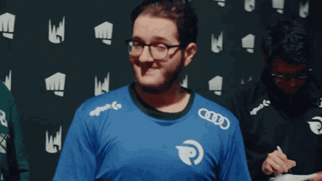 a man wearing glasses and a blue shirt that says audi
