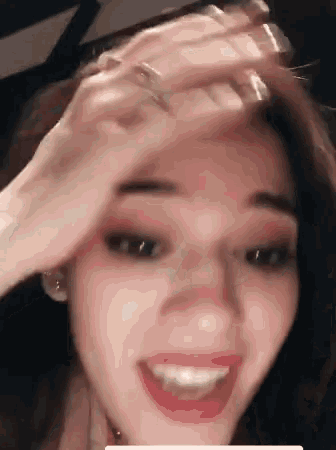 a close up of a woman 's face with her hand on her forehead .