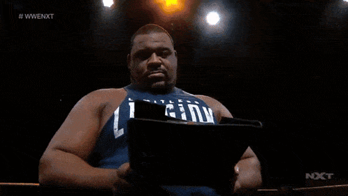 a man is reading a book with a wwe nxt logo in the corner