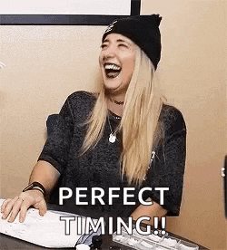 a woman is sitting at a desk laughing while using a computer keyboard .